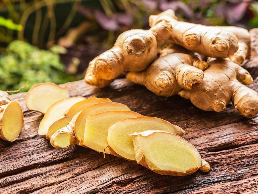 Fresh organic ginger root, whole and sliced, on a wooden surface